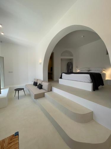 a white bedroom with a bed and a couch at Saliagos villas complex with private pools in Antiparos
