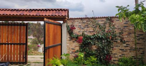 a brick wall with a wooden gate and roses on it at Glamping VILLA - Nueva en Paipa in Paipa