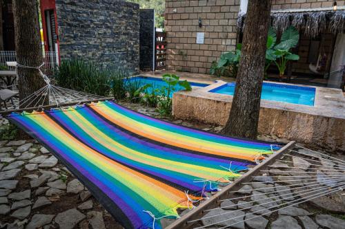 a rainbow colored hammock sitting next to two trees at Tierra Cielo y SoLuna - Cabaña Casona in Santiago