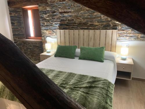 a bedroom with a large bed with two green pillows at Apartamentos Casa Benito in San Tirso de Abres