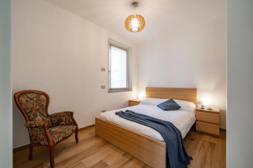 a bedroom with a bed and a chair and a window at Villa Sunrise - Luxury property with pool & large private garden, few steps from the beach, ideal for families and people with mobility issues in Dervio