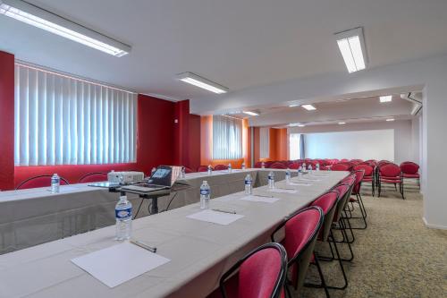 a conference room with a long table and red chairs at Hôtel Akena Poitiers Nord Futuroscope in Chasseneuil-du-Poitou
