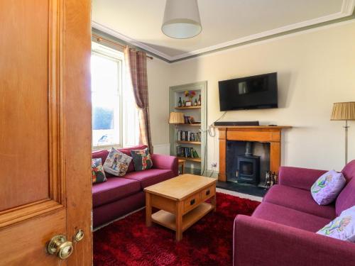a living room with purple couches and a fireplace at Tayview in Killin