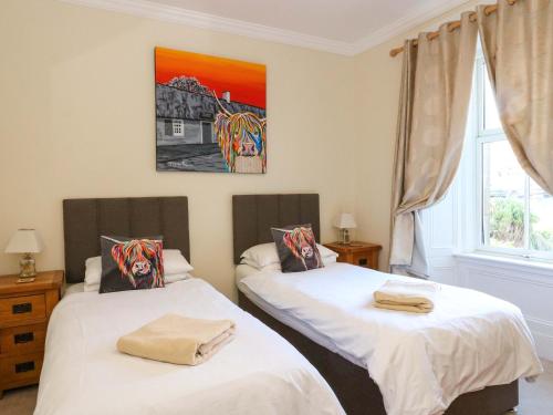 a bedroom with two beds and a painting on the wall at Tayview in Killin