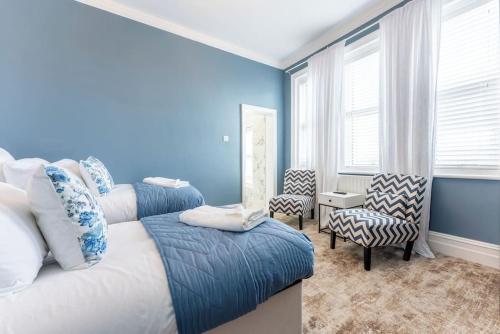 a blue bedroom with two beds and two chairs at The Bell's Self-Service Holiday Flat Bournemouth in Bournemouth