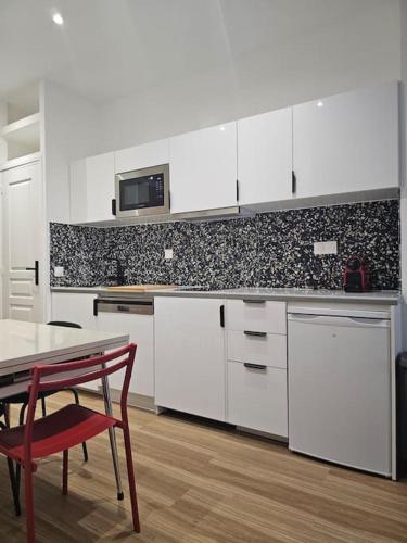 une cuisine avec des placards blancs, une table et une chaise rouge dans l'établissement chic Montmartre apartment, à Paris