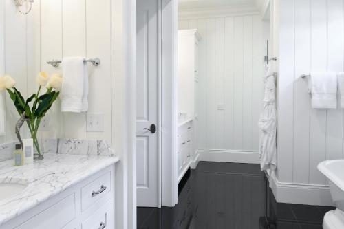 a white bathroom with a vase of flowers on a counter at Signature 5 Bedroom Lagoon Residence 1003 in Bluffton