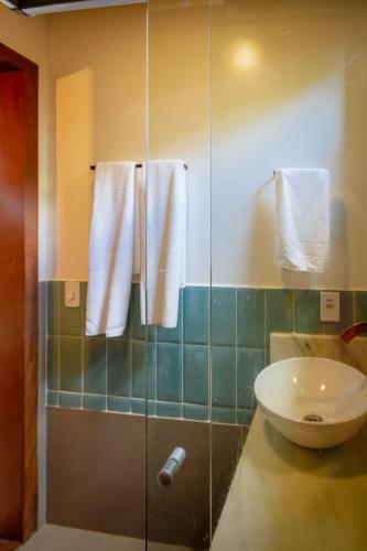 a bathroom with a sink and a shower with towels at Villa Estrela Bungalow in Itacaré