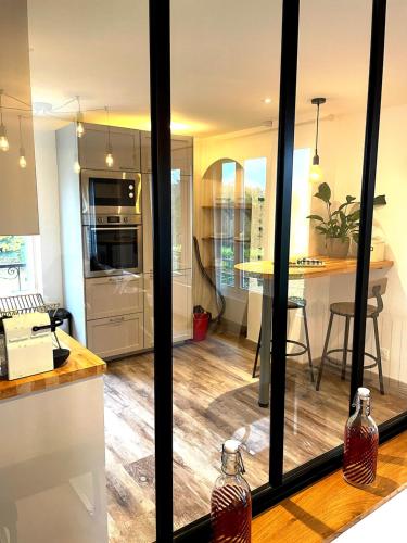 a kitchen with glass doors and a kitchen with a table at Little Paradise - Comfort and Quiet Getaway by the Eure in Montreuil