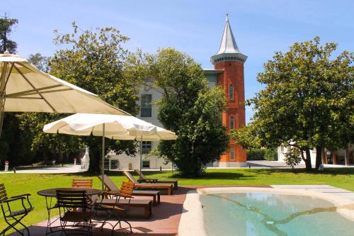 a pool with chairs and umbrellas next to a building at HOTEL BOUTIQUE VILLA DEL MARQUÉS in Muros de Nalón