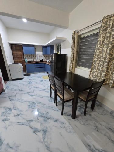 a dining room with a table and chairs and a kitchen at Master Stay in Bengaluru
