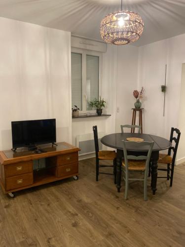 a dining room with a table and a tv at Appartement COSY in Sartilly