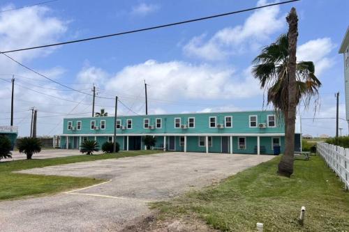 un bâtiment bleu avec un palmier devant lui dans l'établissement The Mark at Surfside #12 HOT TUB!, à Surfside Beach