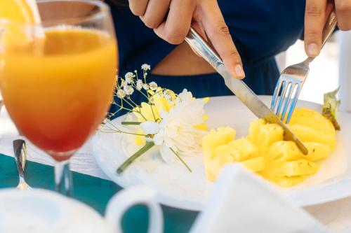 a person eating a plate of food with a drink at Hibiscus Boutique Hotel in Pereybere