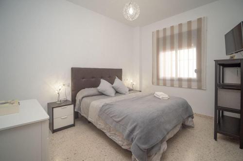ein weißes Schlafzimmer mit einem großen Bett und einem Fenster in der Unterkunft Apartamento ateneo in Sanlúcar de Barrameda