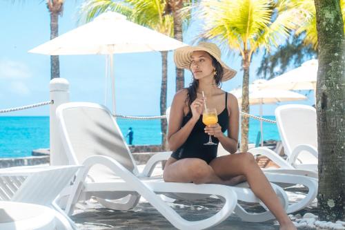 a woman in a bikini sitting on a beach chair with a drink at Hibiscus Boutique Hotel in Pereybere