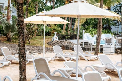 a group of chairs and an umbrella on the beach at Hibiscus Boutique Hotel in Pereybere