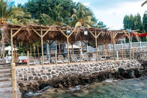 a restaurant with chairs and a thatch roof at Hibiscus Boutique Hotel in Pereybere