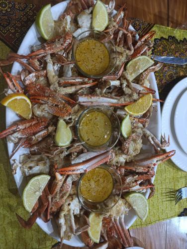 a plate of food with crabs and lemons and dip at Telvina Beach Lodge in Vilanculos