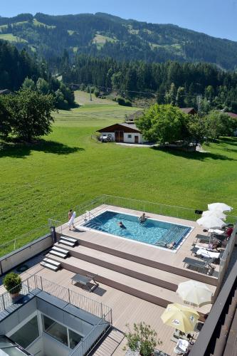 an outdoor swimming pool with a large green field at Wohlfühlhotel Schiestl in Fügen