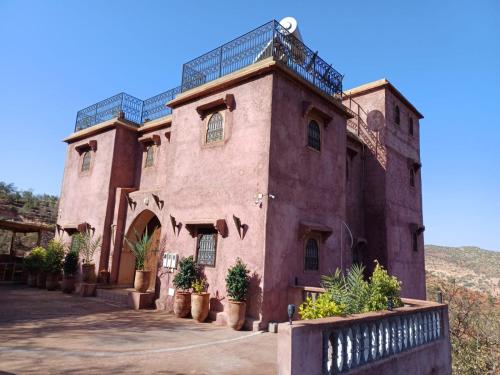 un grand bâtiment en briques rouges avec des plantes en pot dessus dans l'établissement Riad Heermans, à Ouzoud