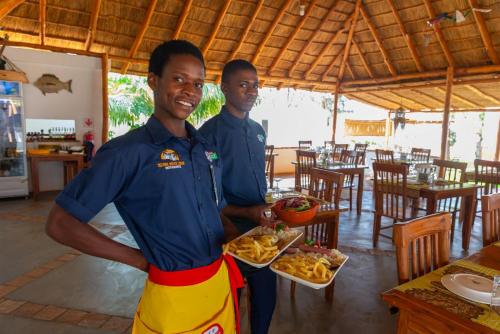 two men standing in a restaurant with plates of food at Telvina Beach Lodge in Vilanculos