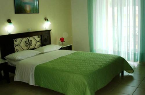 a bedroom with a large bed with a green blanket at Sundy's Studios in Nydri