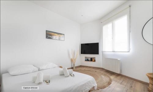 une chambre blanche avec un lit et une télévision dans l'établissement Vivez une expérience méditerranéenne dans cet appartement confortable, à La Seyne-sur-Mer