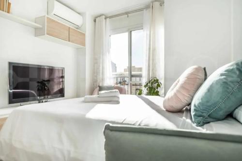 マラガにあるBright Apartment in Central Málaga, 100 m²の大きなベッドとテレビのある白い寝室