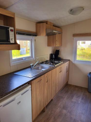 a small kitchen with a sink and a microwave at Strandhuis `Het Kompas` in Lauwersoog