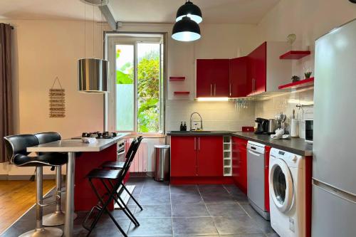 une cuisine avec des placards rouges et un lave-linge/sèche-linge dans l'établissement Le Musset, BNBconciergerie, à Vaulx-en-Velin