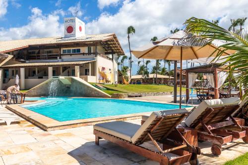 a resort pool with chairs and an umbrella at Sunset Beach Taíba Hotel in Taíba