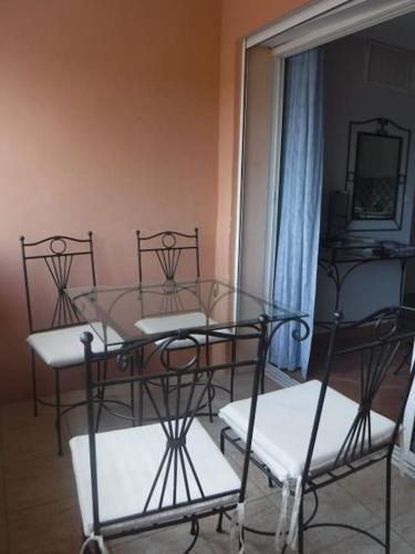a dining room with a glass table and four chairs at Two rooms appartment in residence with pool in Gréoux-les-Bains