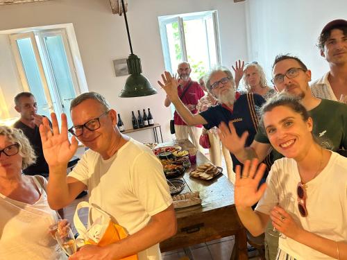 Un groupe de personnes debout autour d'une table, les mains levées dans l'établissement Ostal de la Placette à Padern dans les Hautes Corbières, à Padern
