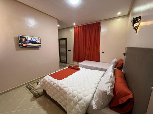 a bedroom with a bed and a tv on the wall at COMPLEXE L'OASIS in Erfoud