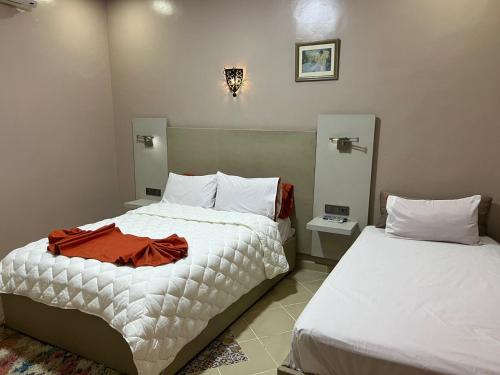 a bedroom with two beds with white sheets at COMPLEXE L'OASIS in Erfoud