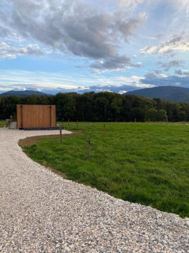 a gravel road leading to a field with a building at Le chalet du hameau in Barbazan
