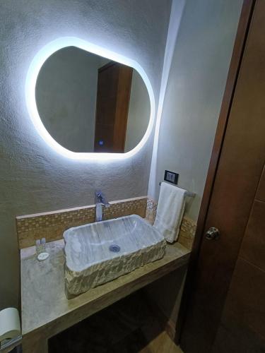 a bathroom with a sink with a round mirror at Casa Lomas Grangelo in Atlixco