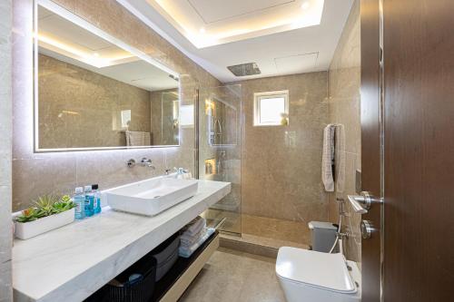 a bathroom with a sink and a toilet and a mirror at Waterfront Villa at Al Hamra with swimming pool in Ras al Khaimah