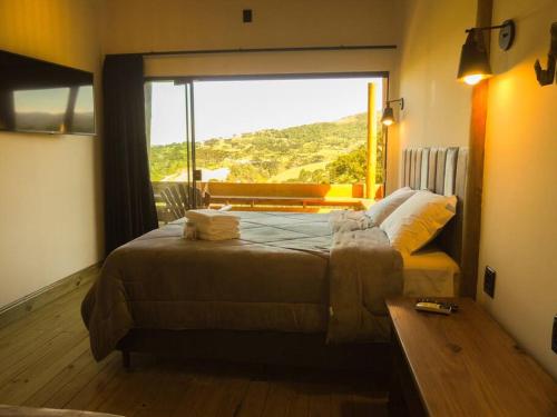 a bedroom with a large bed with a large window at Cabana Mendoza - Busch Camping in Rancho Queimado