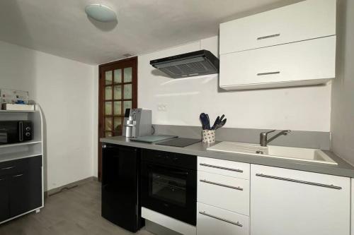 une cuisine avec un évier et une cuisinière dans l'établissement Appartement au calme avec piscine et terrasse, à Carqueiranne