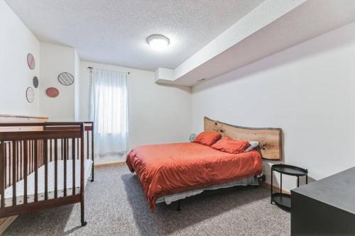 a bedroom with a bed with orange sheets and a crib at Easton Hills in Spicer