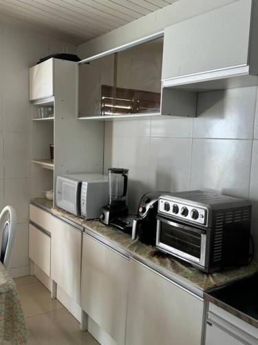 a kitchen with a counter with a toaster oven and microwave at Casa maravilhosa in Natal