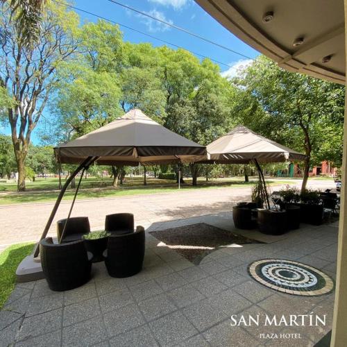two umbrellas and chairs sitting on a patio at San Martin Plaza Hotel in Villa Elisa