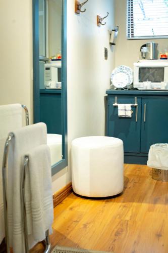 a bathroom with a white ottoman sitting on the floor at Crisp Guest Rooms in Bloemfontein