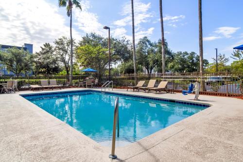 a swimming pool at a resort with chairs and trees at Red Roof Inn PLUS+ Jacksonville – Southpoint in Jacksonville