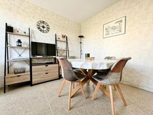 une salle à manger avec une table, des chaises et une horloge dans l'établissement Le Floreal, Apt 4 Prs, 400m plages, stationnement, à Antibes