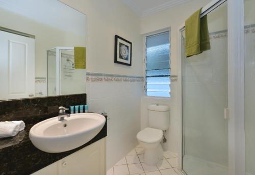 Baño blanco con lavabo y aseo en Reef Villa Port Douglas, en Port Douglas