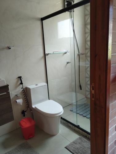 a bathroom with a toilet and a glass shower at Recanto das palmeiras in Espera Feliz