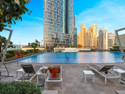a swimming pool with chairs and a city skyline at Luxurious 1BHK Apartments with Marina Waterfront & Dubai Eye Views near JBR, Marina in Dubai